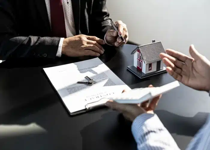 Real estate contract review with home model on desk