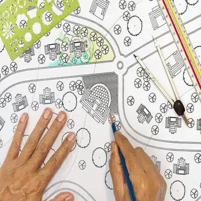 Hands reviewing printed site drawings and layout plans during early project planning