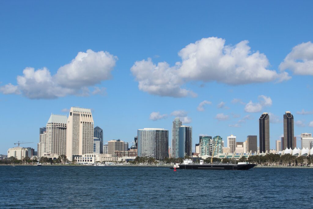 View of San Diego skyline with tall buildings and a ship on a bright day.